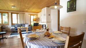 A dining area with a table set for four, a wooden ceiling, and a painting on the wall. - Chasa Val 735C: Quiet, cozy 3 ½-room apartment with fireplace and panoramic views of the national park (Scuol)