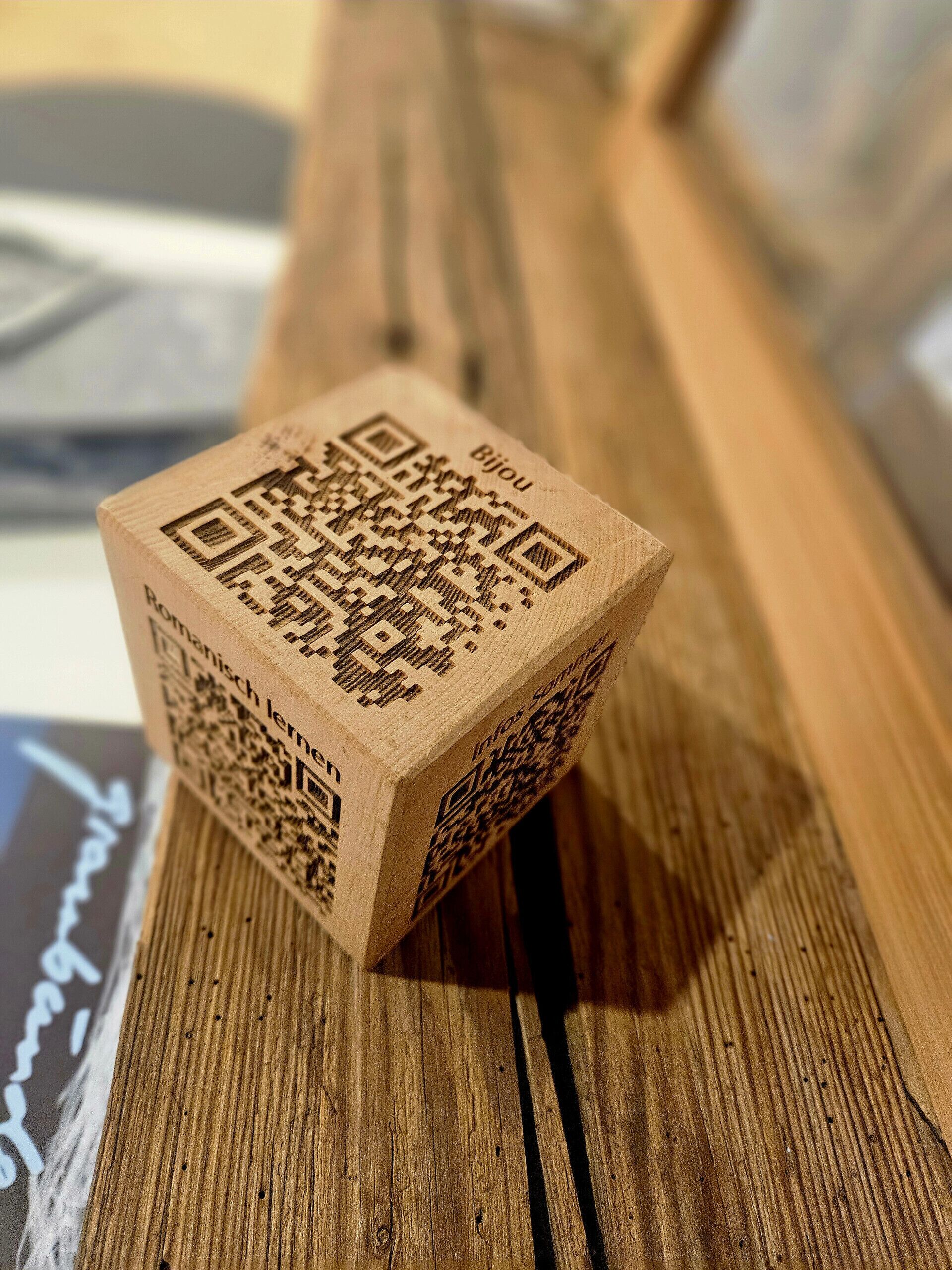 A wooden cube with QR codes and text on its sides.
