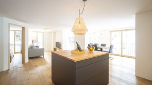 Un espacio habitable amplio con una isla central, un comedor y un balcón con vistas.