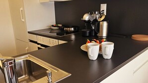Una cucina moderna con lavello in acciaio inox, piano di lavoro nero e mobili bianchi.