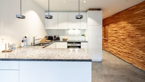 A modern kitchen with white cabinets, granite countertops, and a wooden accent wall.