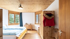 A wooden cabin bedroom with a bed, dresser, and a coat rack.