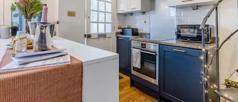 A kitchen with white cabinets, a stove, a microwave, and a window with a view.