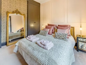 A neatly made bed with pillows and folded towels, a large mirror, and a wardrobe in a well-lit room. - Railway Cottage | Stylish Home - Central Whistable (Whitstable)