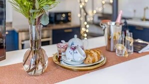 A table with a floral arrangement, a teapot, a croissant, and a glass of water. - Railway Cottage - Stylish & Central Oasis in Whitstable (Whitstable)