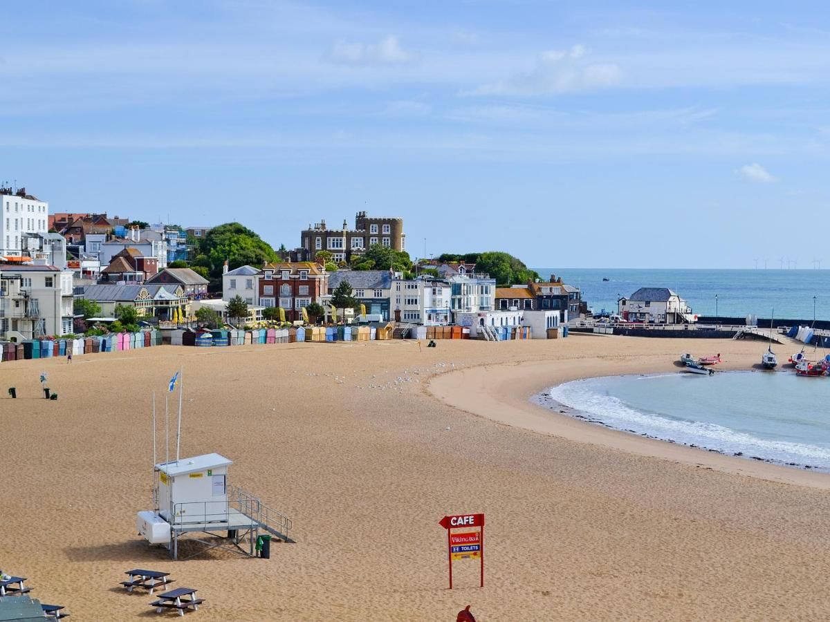 A beach with a lifeguard tower, a cafe sign, and buildings in the background.