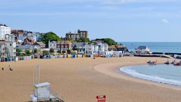 A beach with a lifeguard tower, a cafe sign, and buildings in the background.