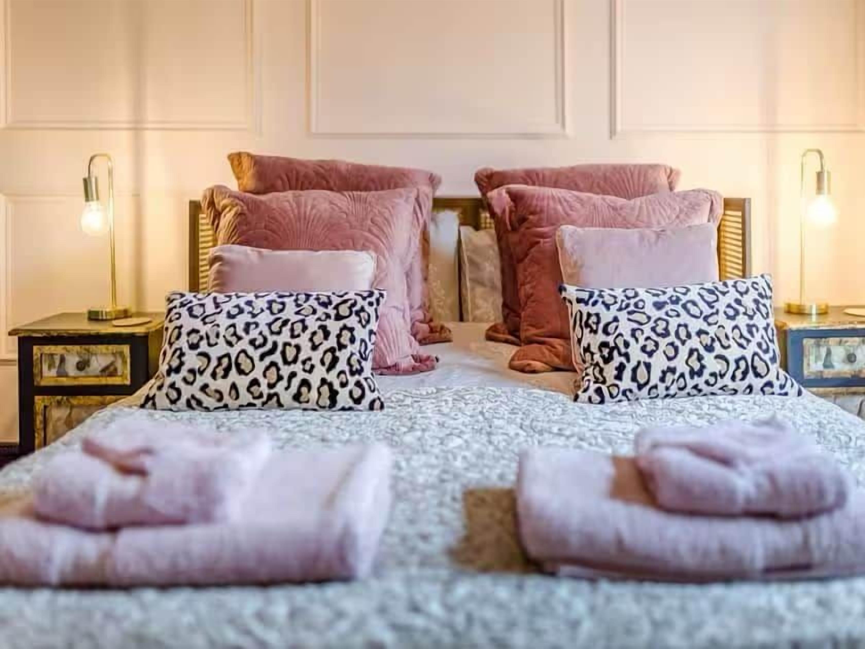 A hotel room with a bed, two nightstands, and a lamp on each side.
