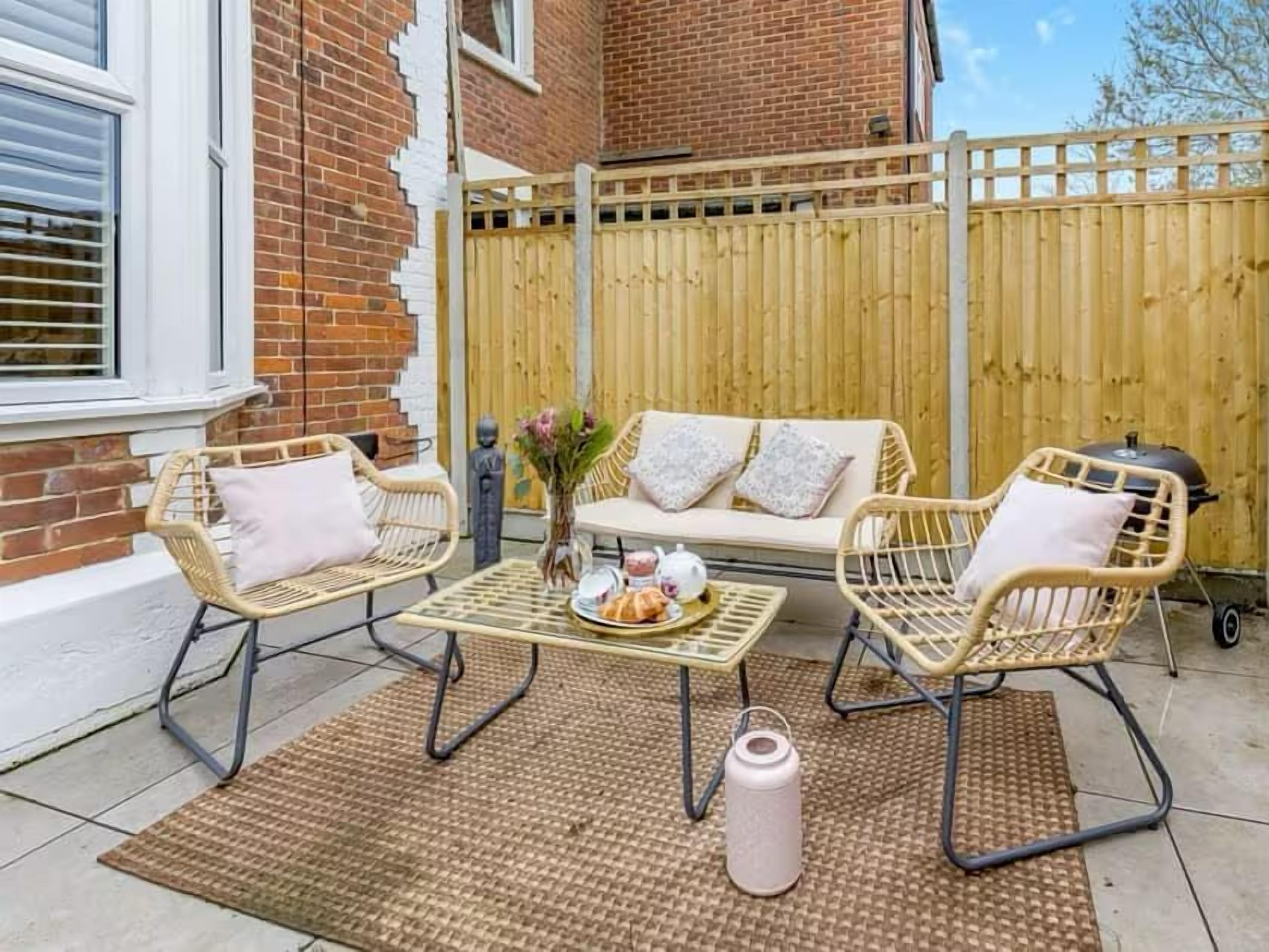 A patio with wicker furniture, a sofa, and a table set with a teapot and cups.