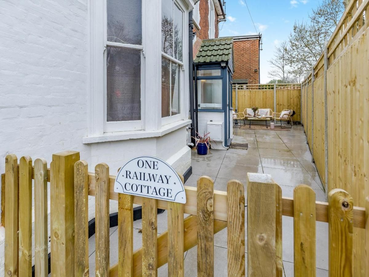 A wooden gate with a sign reading 'ONE RAILWAY COTTAGE.'