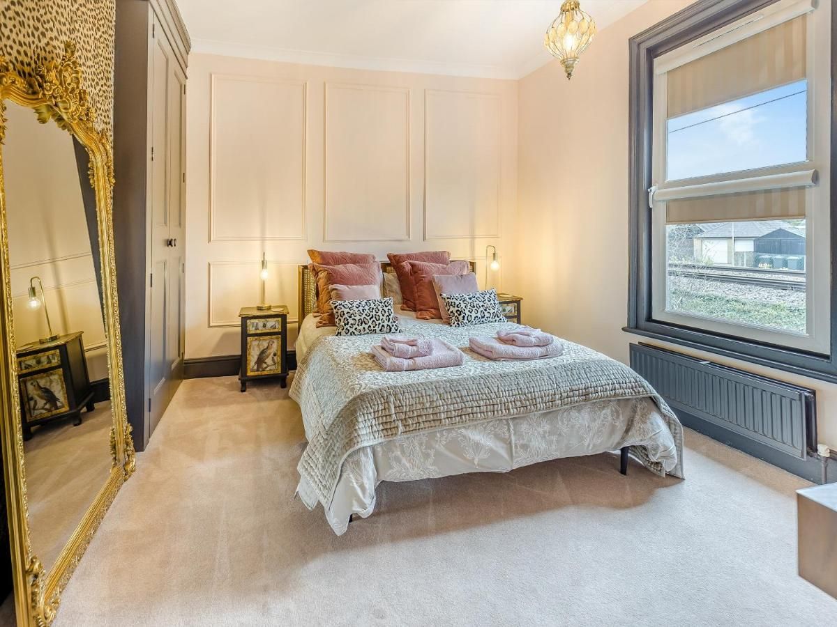 A bedroom with a large bed, a mirror, bedside tables, and a window.