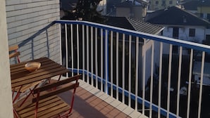 A balcony with a table and chairs, overlooking a residential area with various buildings. - L'Aurora (Novi Ligure)