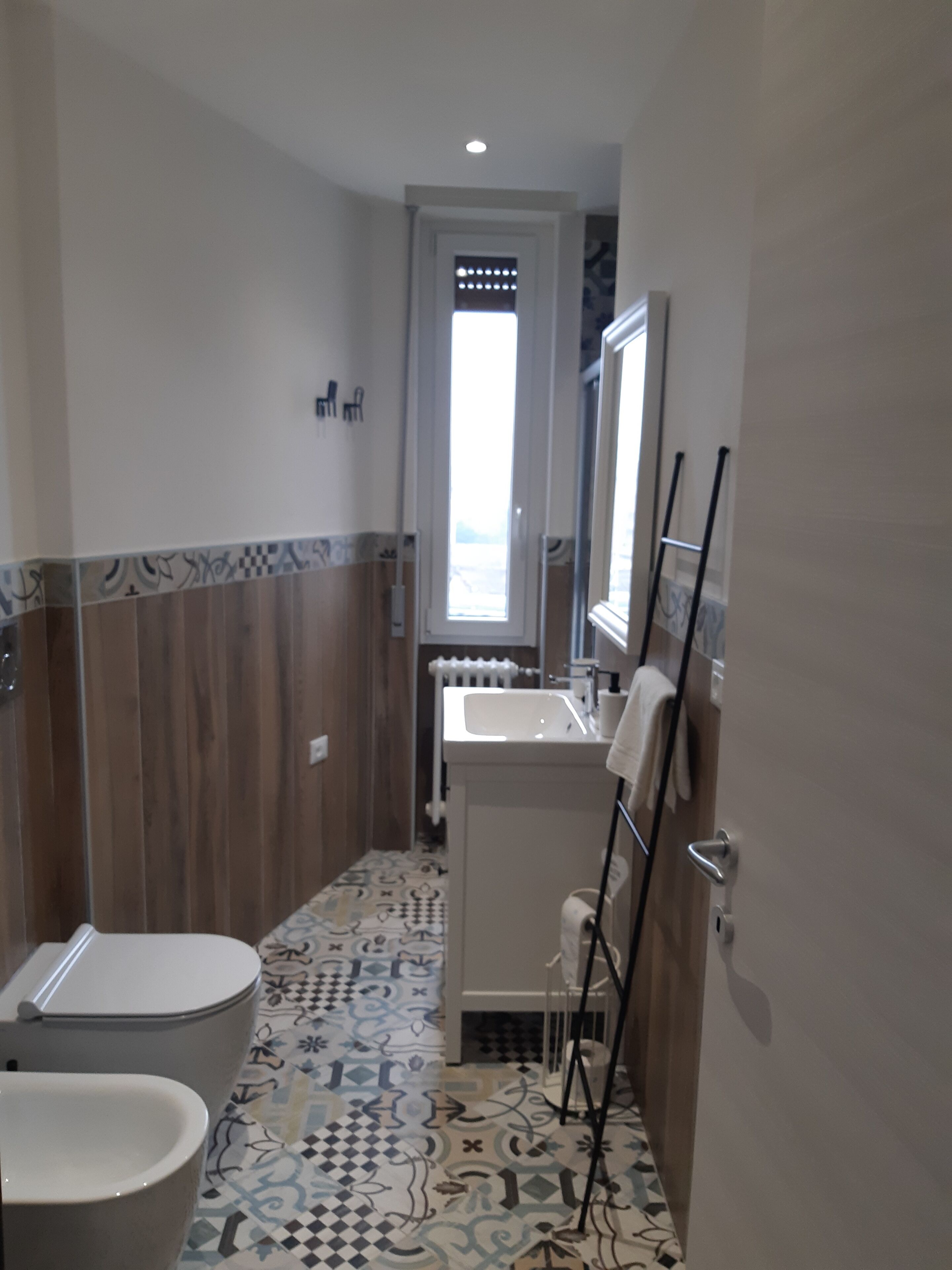 A bathroom with a toilet, sink, and mirror.