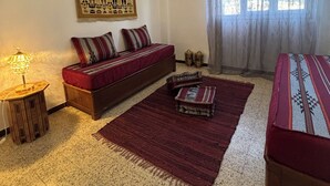 Uma sala de estar com sofá, tapete, abajur e um objeto decorativo na parede.