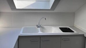 Un tragaluz sobre un lavamanos de cocina con armarios.