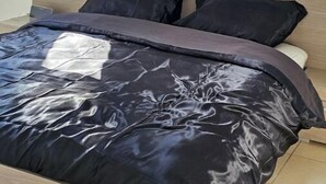 Una cama con una colcha de diseño blanco y negro en una habitación con tragaluz.