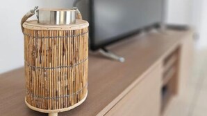 Una sala moderna con un mueble bajo de madera para el televisor, un televisor de pantalla plana y una lámpara de estilo cesta tejida sobre el mueble.