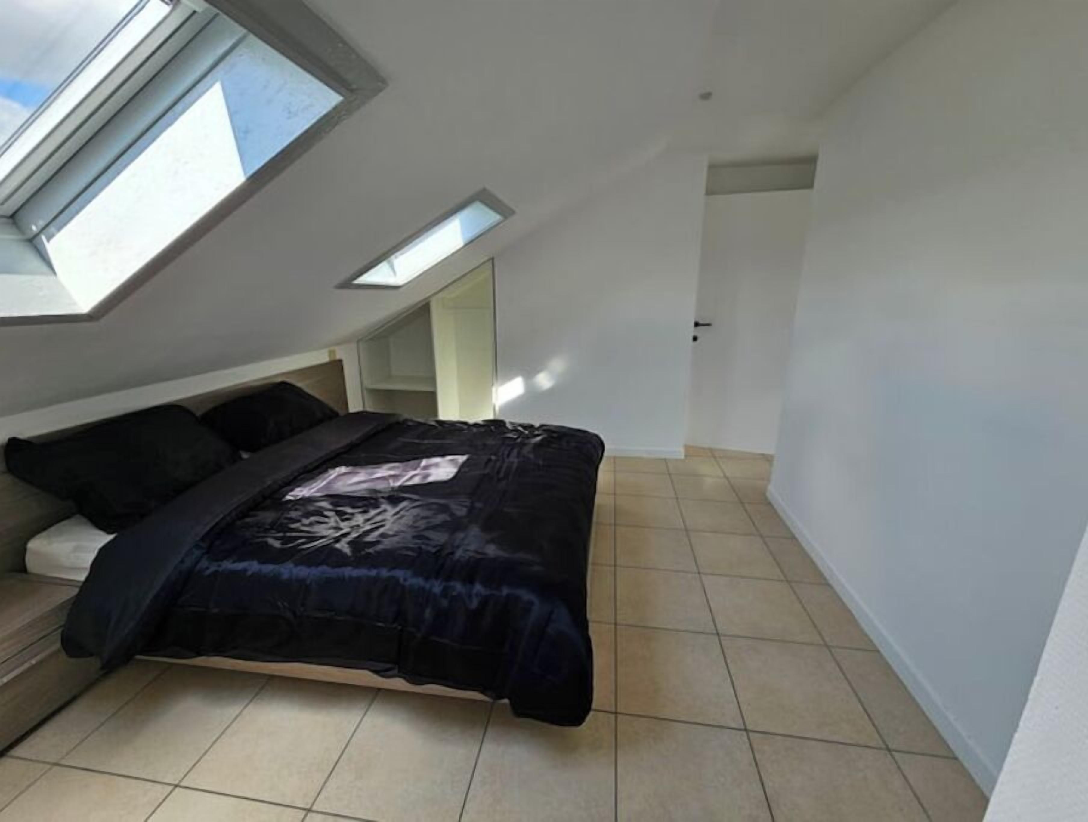 Ein Schlafzimmer mit Dachfenster, einem Bett, einer eingebauten Sitzbank und einem Kleiderschrank.