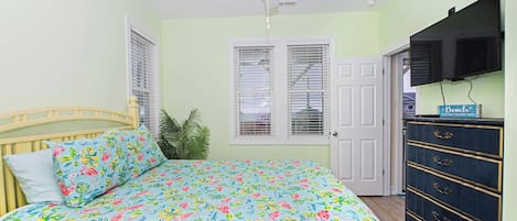 A bedroom with a bed, a ceiling fan, a dresser, and a door.