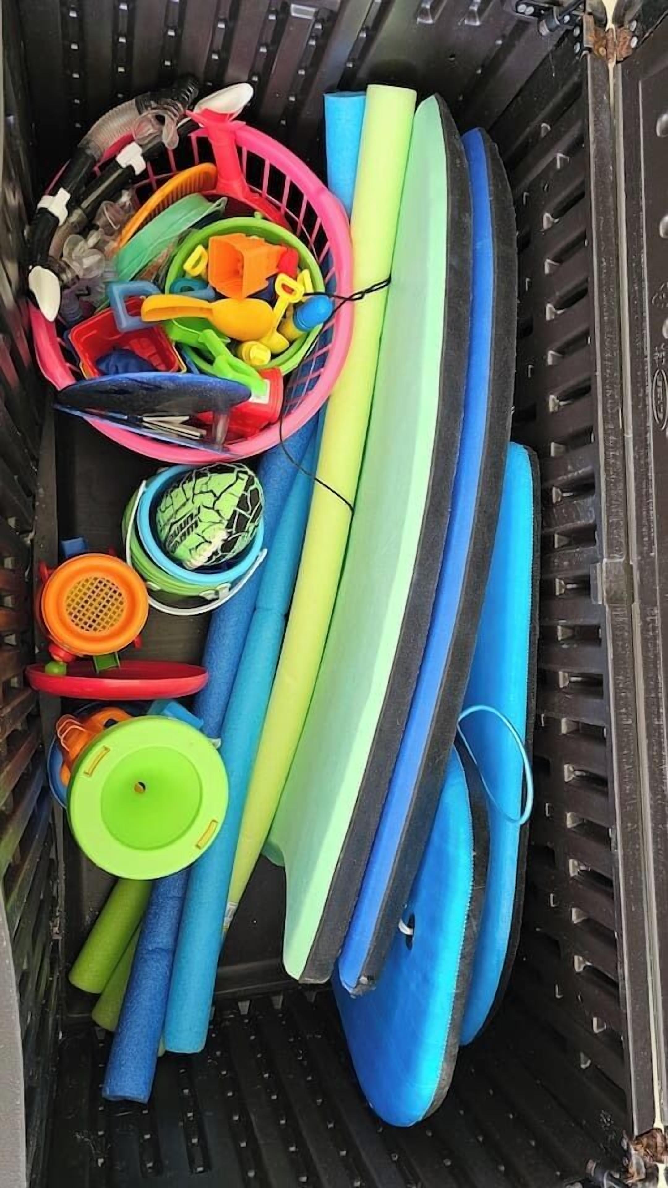 A storage area with various items including a pink basket, colorful paddles, and a blue kayak.