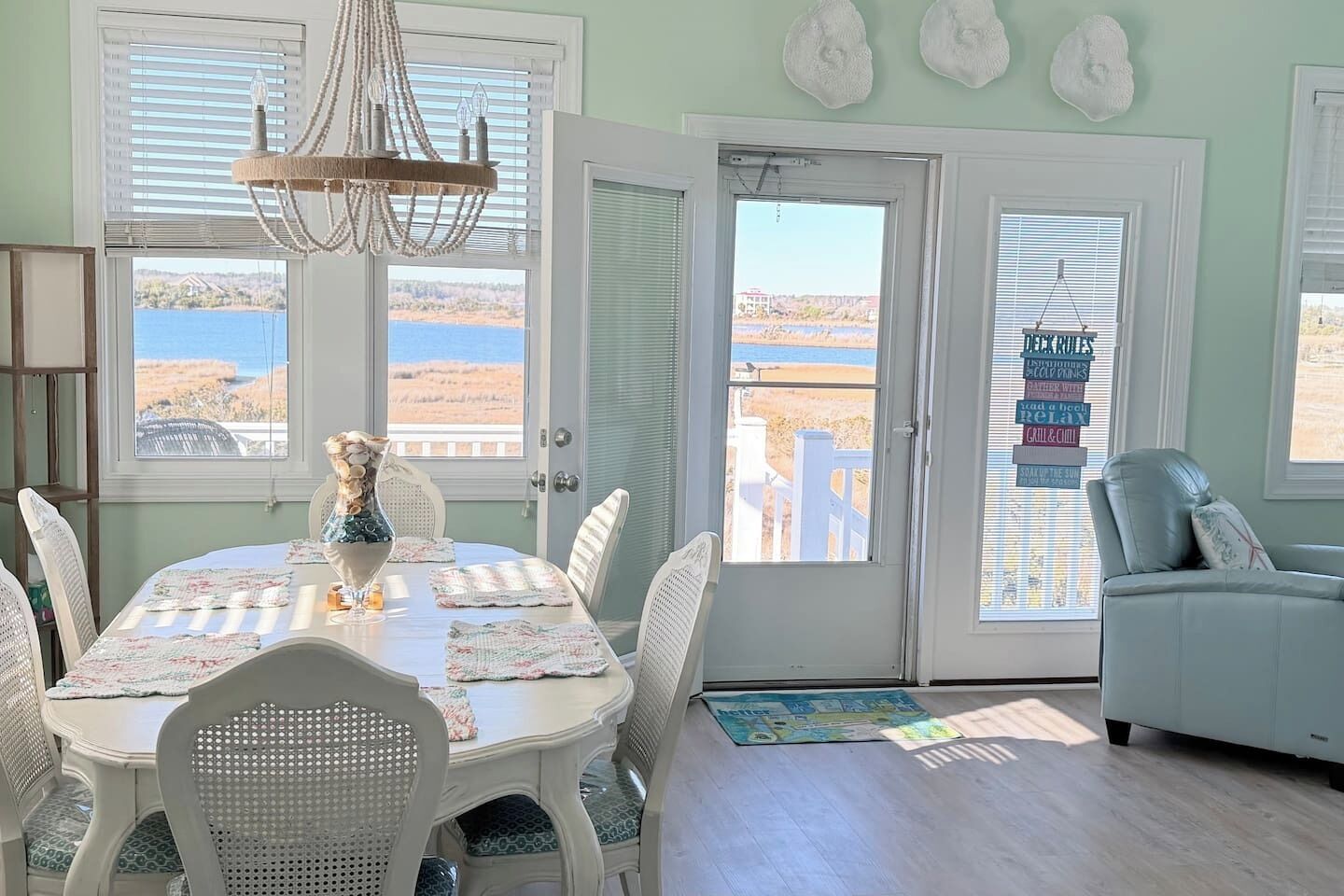 A dining area with a table set for six, surrounded by white wicker chairs.