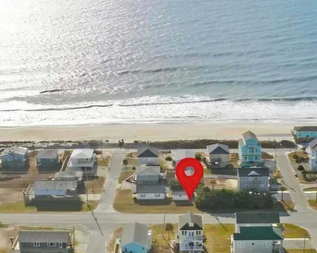 A coastal residential area with houses, a beach, and a red location marker.