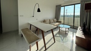 Una sala moderna con un sofá, una mesa de comedor, un banco, una mesa de centro de vidrio y un televisor.