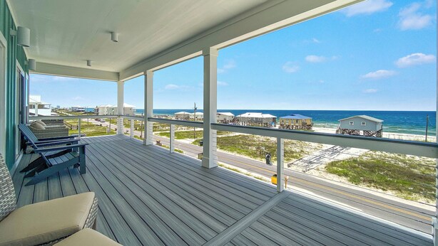 Un espacio al aire libre cubierto con una terraza de madera, sillas de descanso y vista a la playa y al océano.