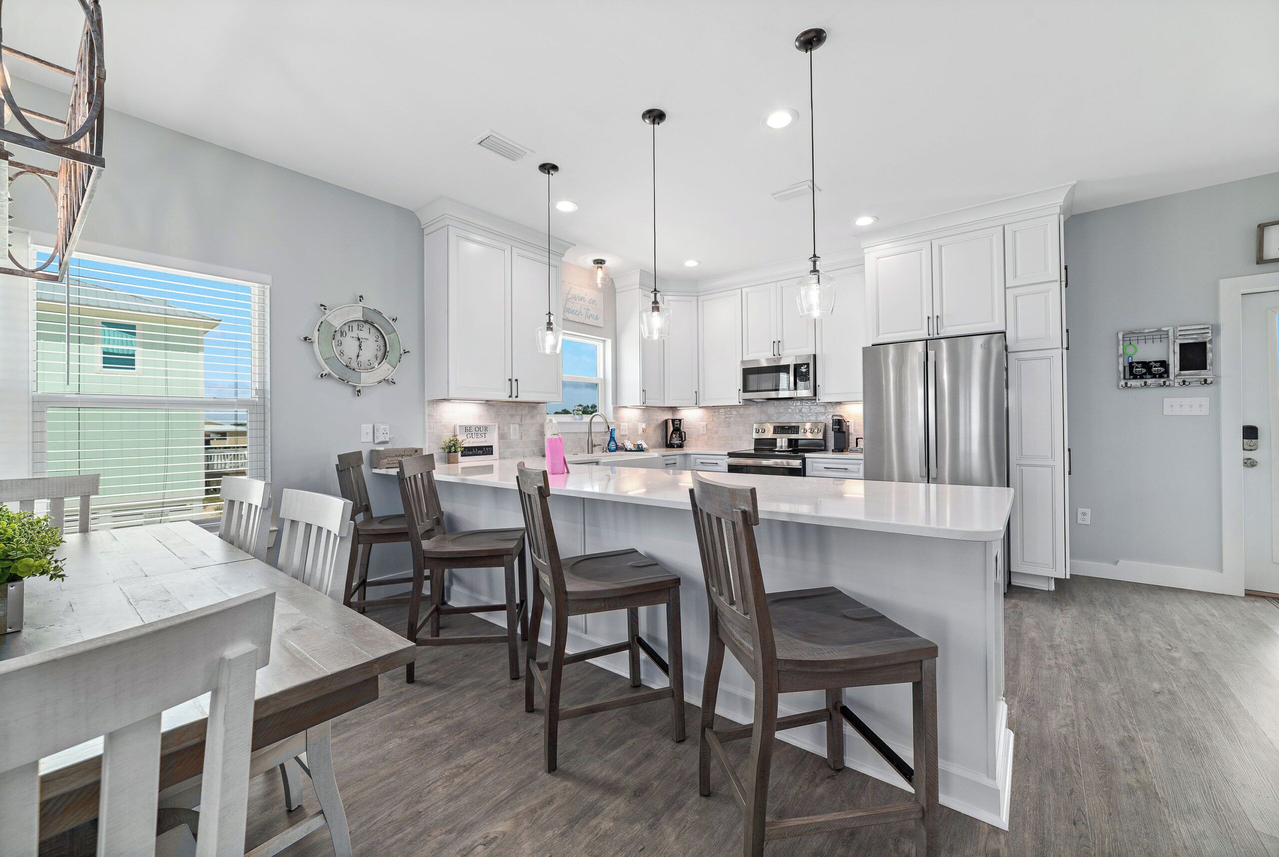 A modern kitchen with white cabinets, stainless steel appliances, and a large island with bar stools.