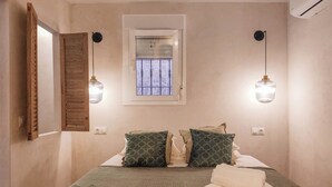 Una camera da letto con un letto, cuscini, una finestra e due lampade a parete.