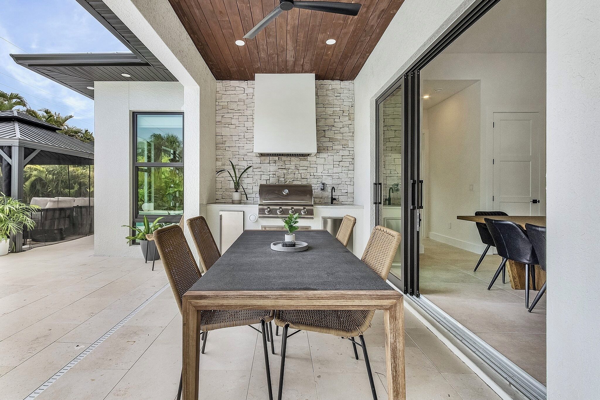 Une cuisine moderne avec un pare-feu en pierre, un plafond en bois et une grande fenêtre.