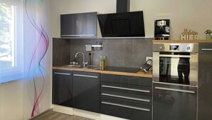 Una cocina moderna con armarios negros, un horno de acero inoxidable y un microondas.