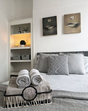 A neatly arranged bedroom with a bed, pillows, and a bedside table with towels. - 3 Bedroom House Near Liverpool Football Stadium (Liverpool)