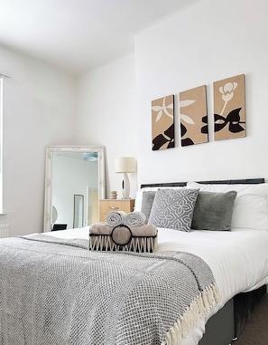 A bedroom with a large bed, a mirror, a bedside table, and wall art. - 3 Bedroom House Near Liverpool Football Stadium (Liverpool)