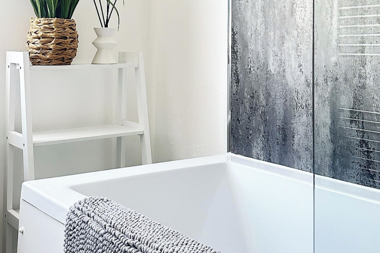 A modern bathroom with a white bathtub, a woven basket, and a white shelf.