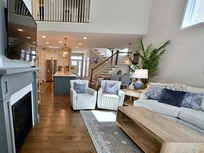 Ein geräumiger Wohnbereich mit Kamin, einer Couch und einem Essbereich mit Stühlen.