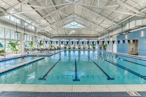 An indoor swimming pool with clear lanes, a high ceiling with metal beams, and potted plants along the sides. - New Listing: Bayside Resort Fenwick Island at The Point - Luxury (Selbyville)