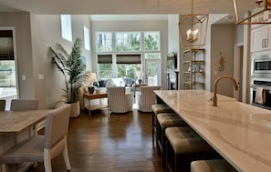 A spacious kitchen with a large island, wooden flooring, and a dining area with striped chairs.