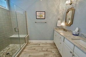 A bathroom with a glass shower enclosure, a framed artwork on the wall, a towel rack, a sink with a marble countertop, and a mirror. - New Listing: Bayside Resort Fenwick Island at The Point - Luxury (Selbyville)