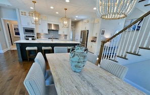 A modern kitchen with white cabinets, a central island, and a dining area with a wooden table and chairs. - New Listing: Bayside Resort Fenwick Island at The Point - Luxury (Selbyville)