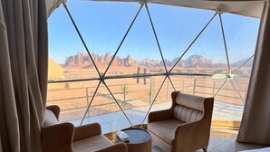 A tented room with a bed, two sofas, and a small table. - Jabal Rum camp (Wadi Rum)