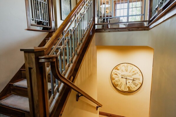 A staircase with wooden railings and a wall-mounted clock labeled 'ANTIQUES.' - Luxury villa w/ lake+mtn views+private theatre! (Grand Lake)