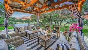 Une terrasse extérieure aménagée avec des meubles en osier, une table en bois et une vue sur un parc.