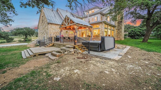 Une grande maison en pierre dotée d’un porche abrité et d’un espace extérieur aménagé pour s’asseoir.