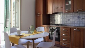 A modern kitchen with wooden cabinets, a tiled backsplash, and a dining area with white chairs and a table.