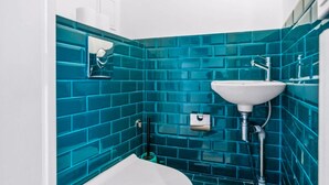 Une salle de bain avec un lavabo blanc, des murs recouverts de carreaux bleus et une baignoire blanche.