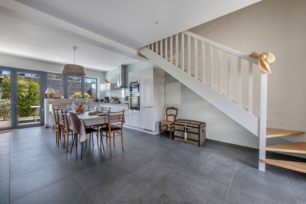 Una cocina moderna con comedor, una escalera y vistas al exterior.