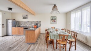 Une cuisine moderne avec des meubles en bois, un îlot central et un coin repas avec une table dressée pour six personnes.