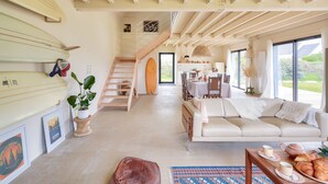 Un grand salon comprenant un canapé, une table basse et des planches de surf accrochées au mur.