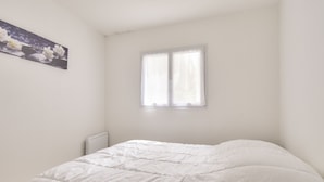 A bedroom with a bed, a window, and a wall-mounted picture.